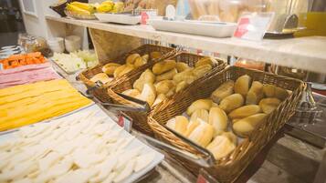 A buffet with various food items including bread, pastries, and sliced meats.