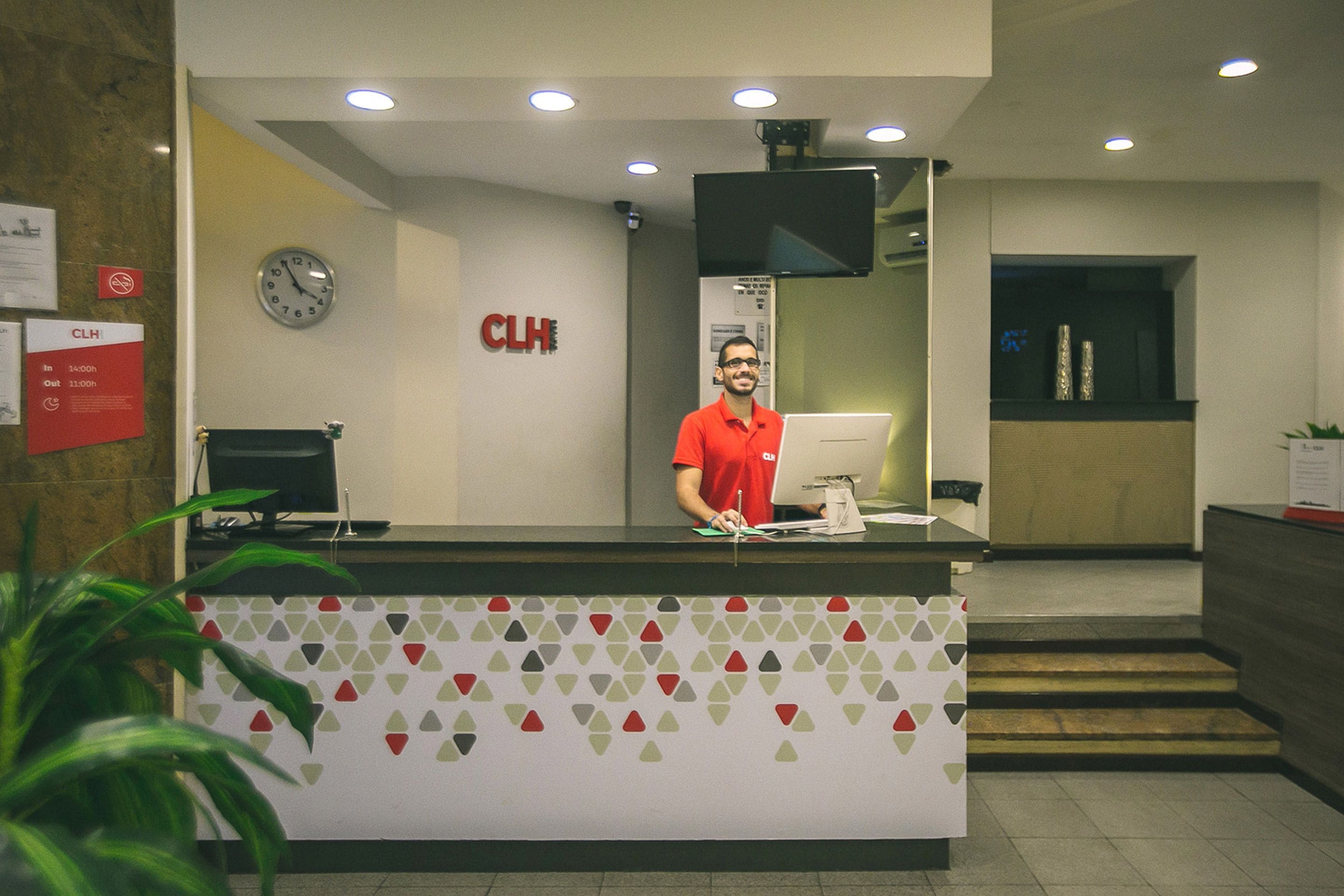 A reception desk with a clock, a monitor, and a sign indicating closing hours.