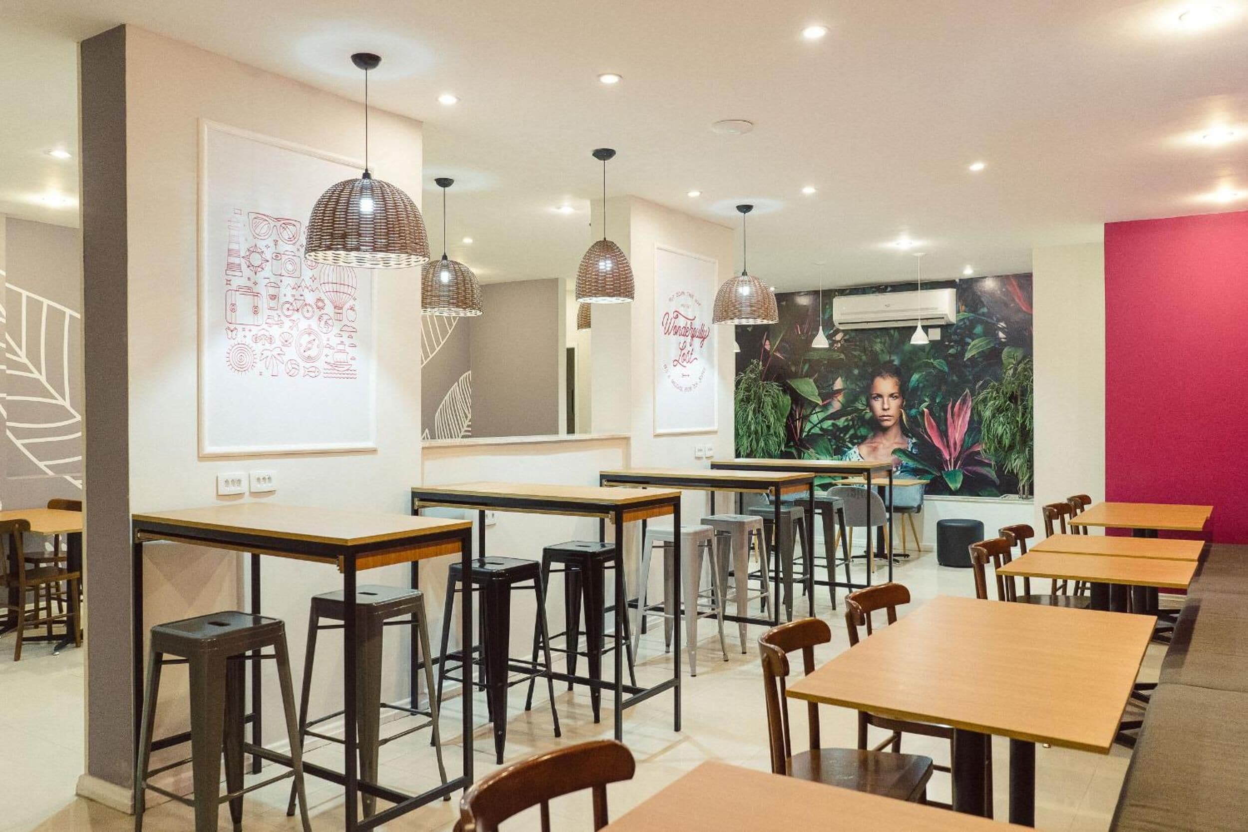 Un comedor moderno con varias mesas y sillas, lámparas colgantes y obras de arte en las paredes.
