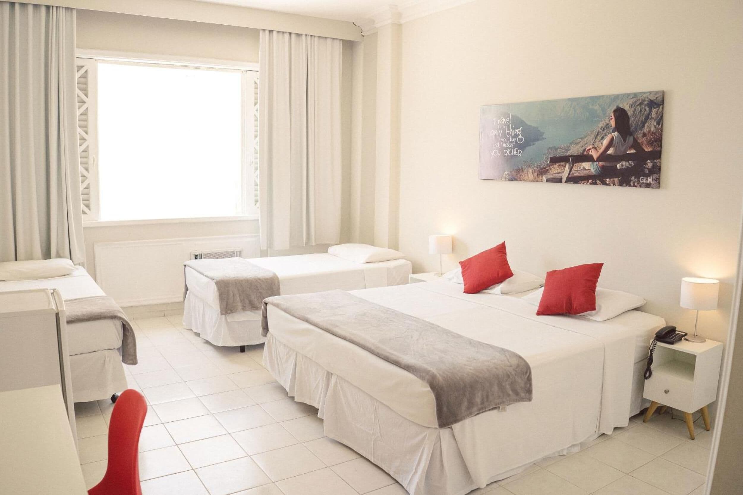 Ein Hotelzimmer mit zwei Betten, einem Schreibtisch, einem Stuhl und einem Bild an der Wand.