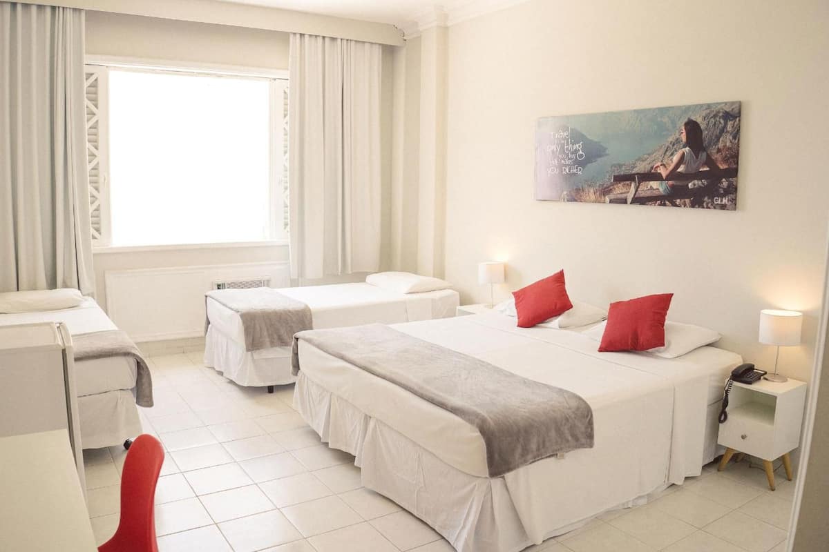 A hotel room with two beds, a desk, a chair, and a painting on the wall.