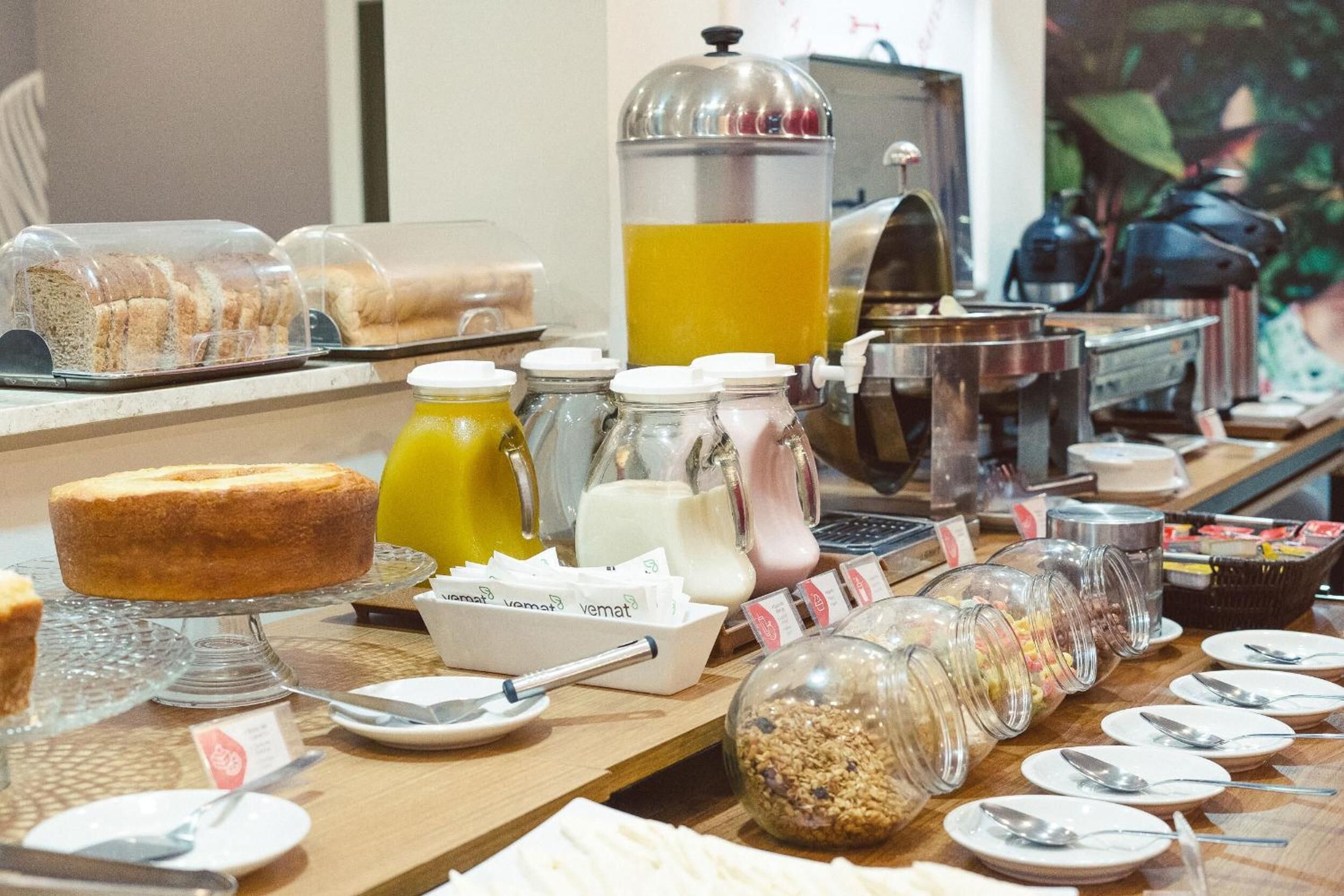 Un buffet proposant une variété de plats, notamment des gâteaux, des fruits et des boissons.