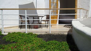Een balkon met een tafel, stoelen, een houten deur en een witte parasol.