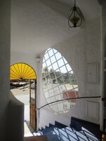 Una escalera con un ventanal grande y un abanico amarillo.