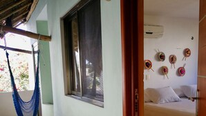 A room with a bed, a hammock, and a window.