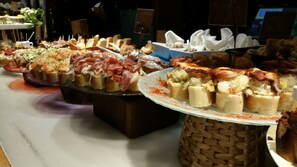 Un bufé con diversas opciones de comida, incluyendo pan, carnes y mariscos.