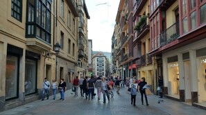 Una calle urbana concurrida con peatones y comercios, incluyendo un letrero visible de 'LARA' y una tienda 'FANTASTIC'.