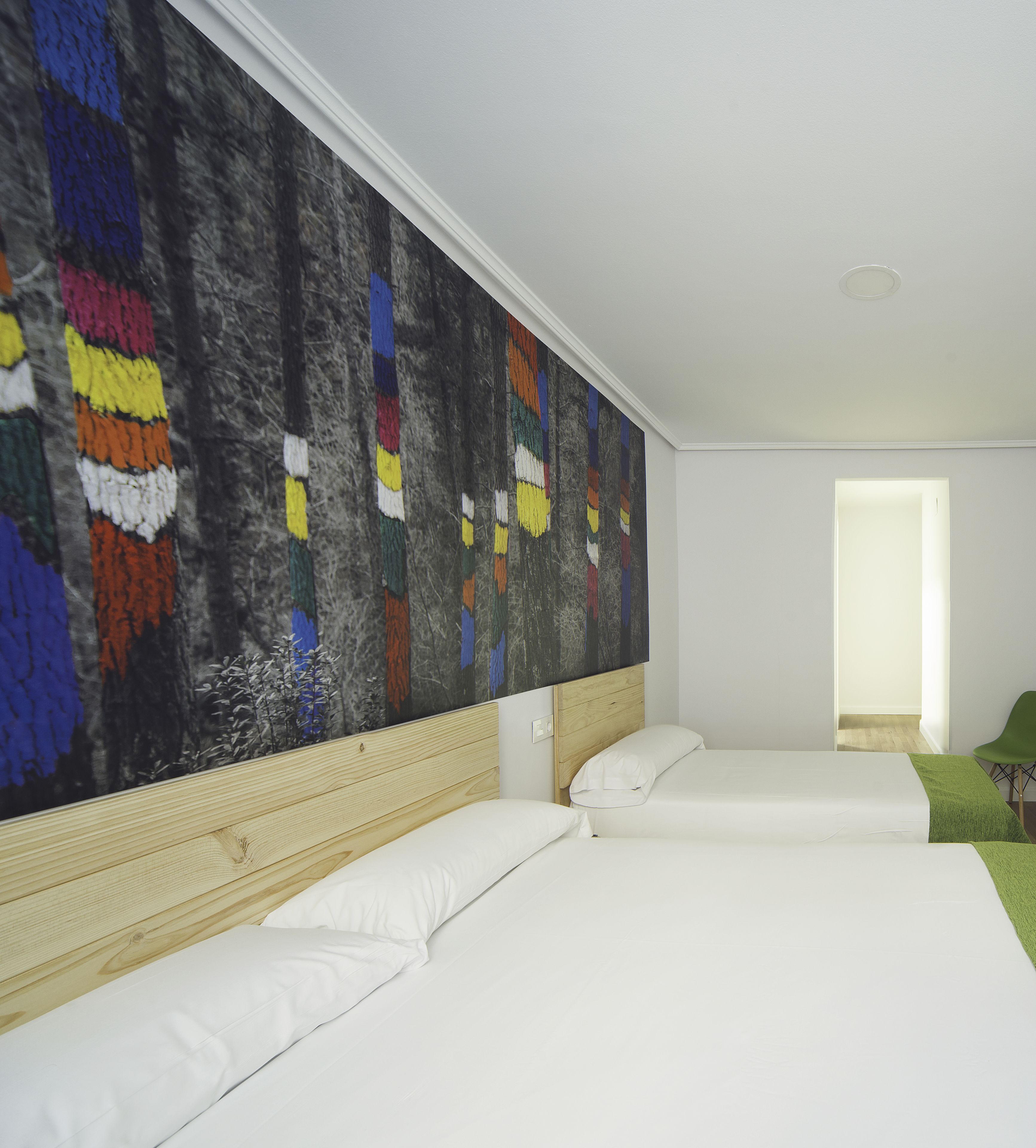 Ein Hotelzimmer mit zwei Betten, einem großen abstrakten Gemälde an der Wand und Blick ins Freie.