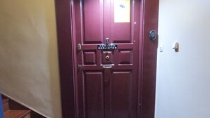 Una puerta de madera con un letrero que dice "Pension Serantes" y un felpudo en la entrada con el texto "Casual Se Antes".
