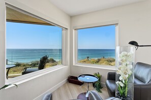Enjoy a panoramic ocean view from the large window in this stylish room, featuring a comfortable seating area with a sofa and small table.