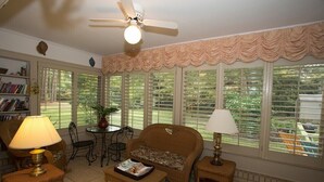 Un salon confortable avec un ventilateur de plafond, un canapé, une table basse et une bibliothèque.