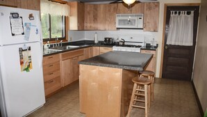 A kitchen with wooden cabinets, a central island, a microwave, and a refrigerator.