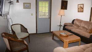 A living room with a door, two chairs, a sofa, a lamp, and a coffee table.