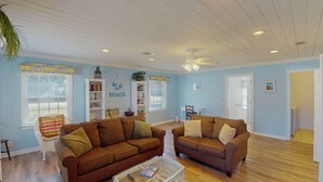 A living room with two brown sofas, a glass coffee table, and a bookshelf.