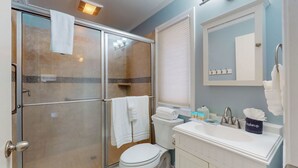Ein Badezimmer mit Duschkabine, Toilette, Waschbecken mit Spiegel und Handtuchhalter.