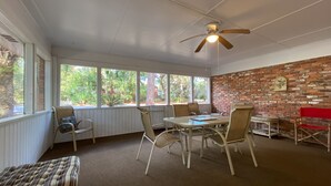 A sunroom with a brick wall, large windows, and a ceiling fan. - Island Pines 3 bedrooms, 2 bathrooms (Jekyll Island)
