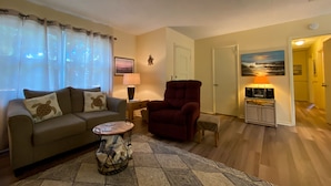 A living room with a sofa, armchair, coffee table, and a painting on the wall. - Island Pines 3 bedrooms, 2 bathrooms (Jekyll Island)