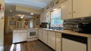A kitchen with white cabinets, a stove, a dishwasher, and a coffee maker. - Island Pines 3 bedrooms, 2 bathrooms (Jekyll Island)