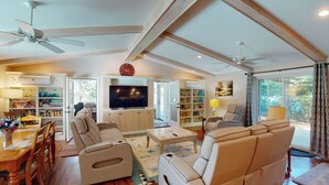 A spacious living room with a large TV, comfortable seating, and a ceiling fan.