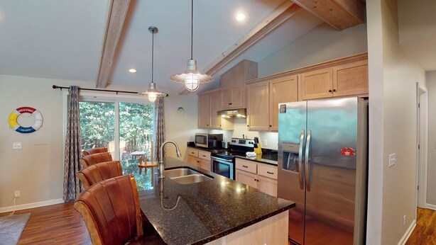 A modern kitchen with a central island, stainless steel appliances, and wooden cabinets.