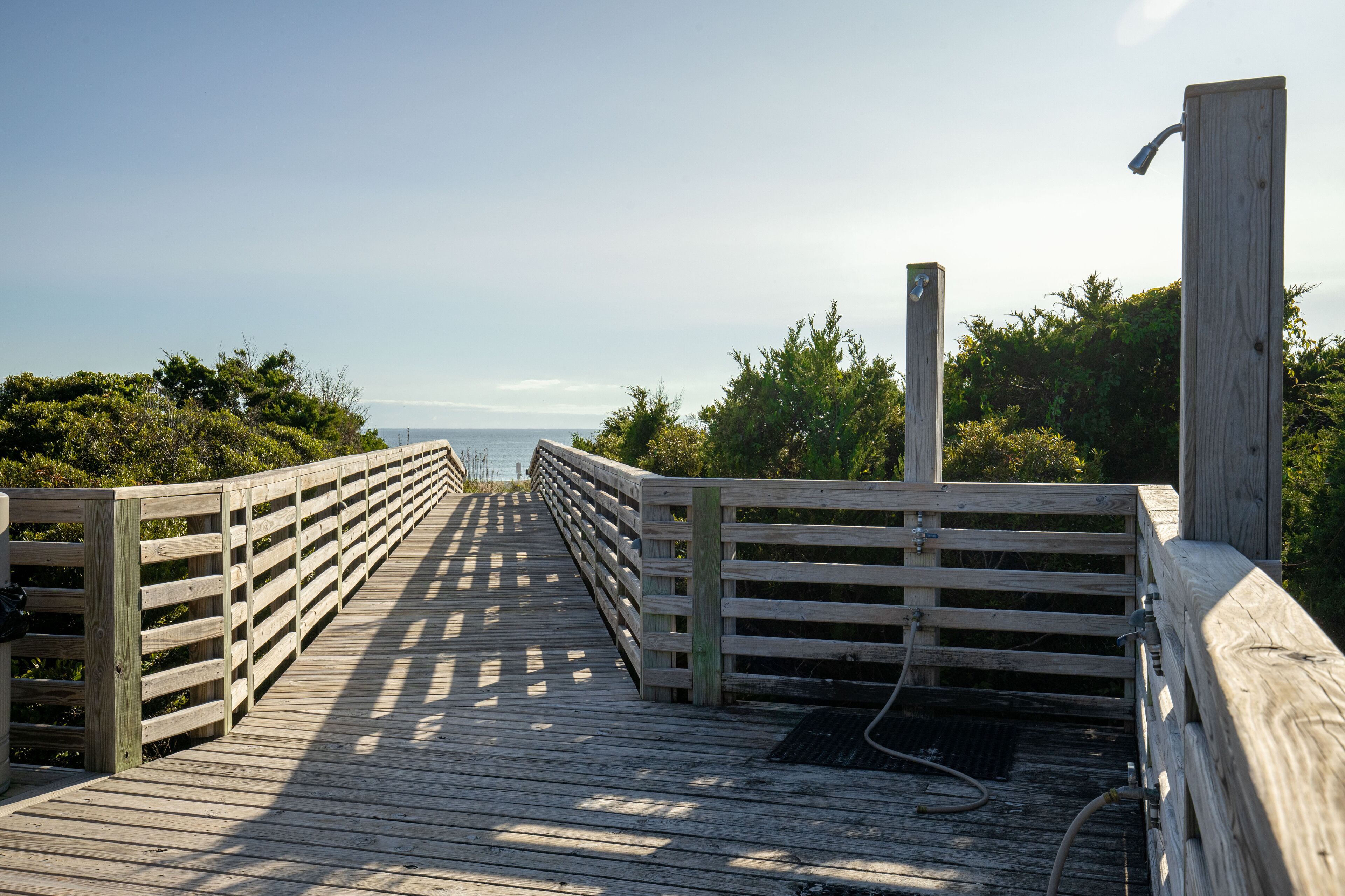 Ein hölzerner Steg führt zum Meer, beidseits mit Geländern.