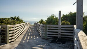 En träpromenad som leder ner till havet, med räcken på båda sidor.