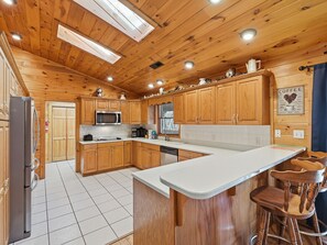 A wooden-paneled kitchen with a stainless steel refrigerator, a microwave, and a coffee machine.