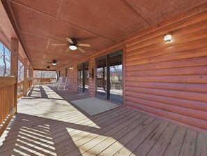A wooden deck with a ceiling fan, a bench, and a rocking chair.