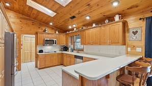 A wooden-paneled kitchen with a stainless steel refrigerator, a microwave, and a coffee machine.