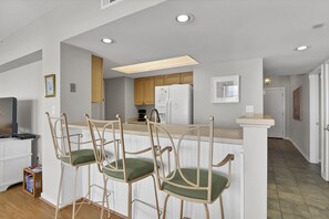 Una cocina con armarios de madera, un refrigerador blanco y una barra con dos sillas.