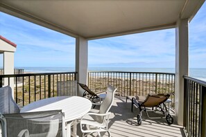 A covered outdoor area with a table and chairs, overlooking a beach. - DR 1405 - Beautiful oceanfront condo with tennis, pool and easy beach access (Wrightsville Beach)