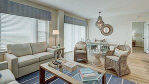 Un salon comprenant un canapé, deux fauteuils en osier, une table basse et un coin repas avec une table et des chaises.
