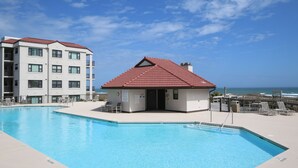Une piscine, avec un bâtiment aux toits rouges situé à proximité, un poste de surveillance pour les sauveteurs et une vue sur l’océan.