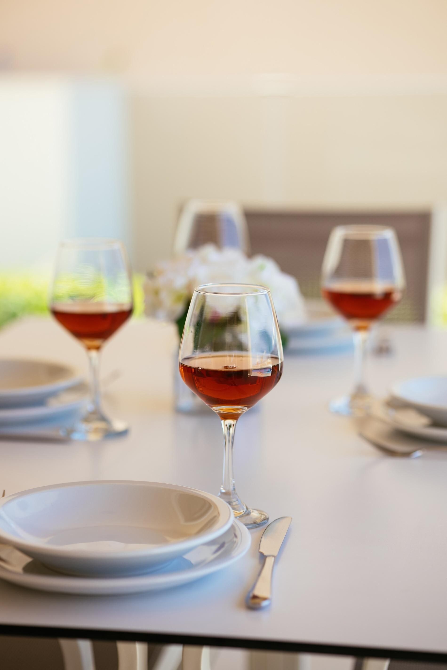 A dining table with two wine glasses, a plate, and a spoon.