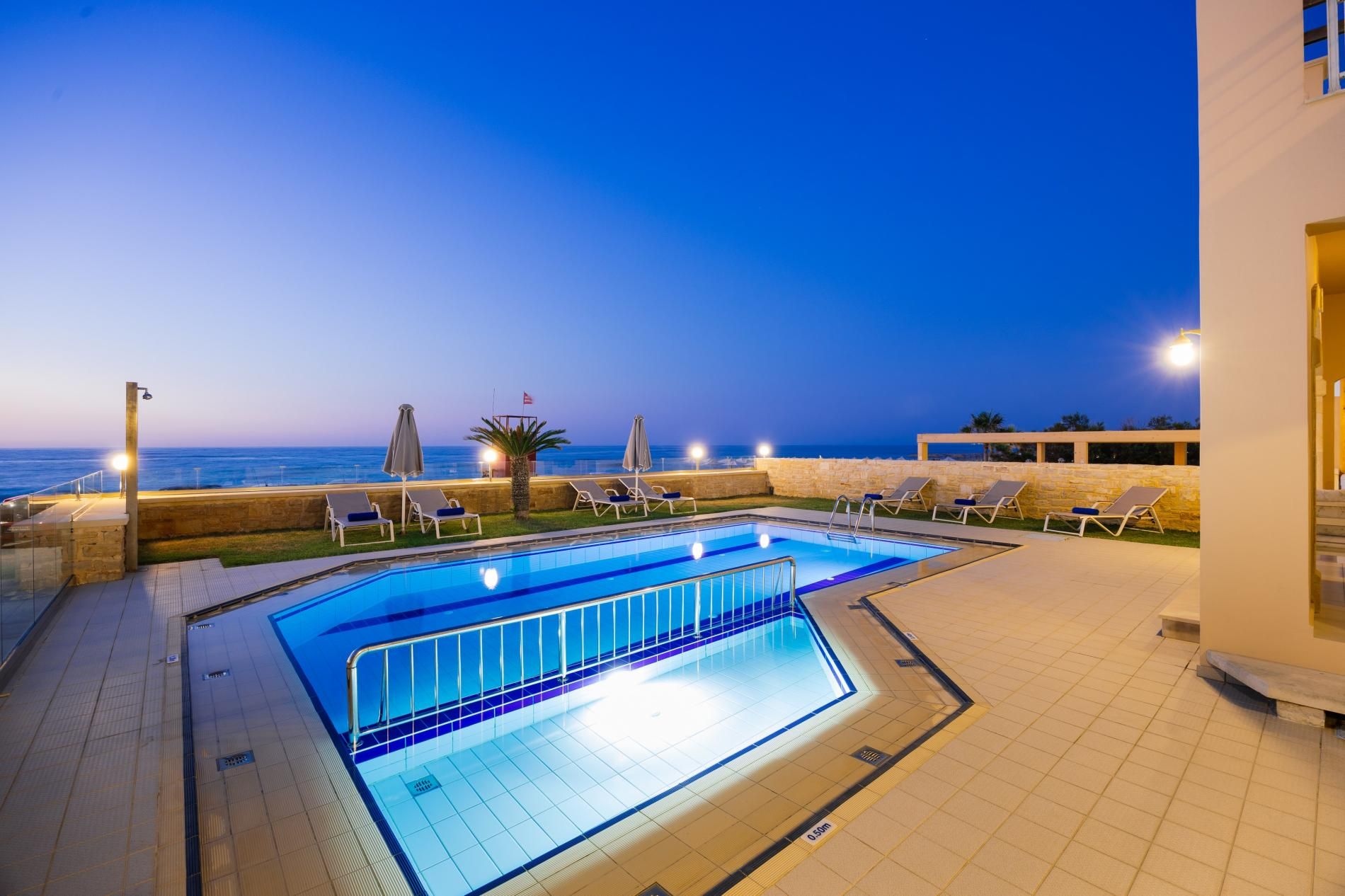 A swimming pool with a view of the sea at dusk.