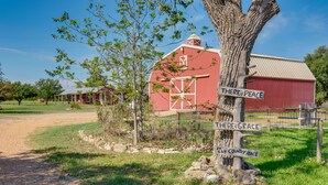 Un paysage rural avec une grange rouge, un panneau indicateur portant les inscriptions « Ici règne la paix » et « Ici se trouve la grâce », et un chemin de terre menant à la grange.