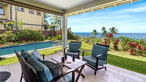 A covered patio with a pool, outdoor furniture, and a view of the ocean.