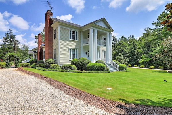 A two-story house with a central chimney, a covered porch, and a well-maintained lawn.