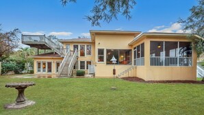 A two-story house with a balcony, a staircase, and a well-maintained lawn. - Beachfront Bliss 4 bedrooms, 3 bathrooms (Jekyll Island)