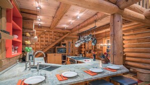 Une cuisine de style rustique, avec un îlot central, des armoires en bois et des ustensiles de cuisine suspendus.
