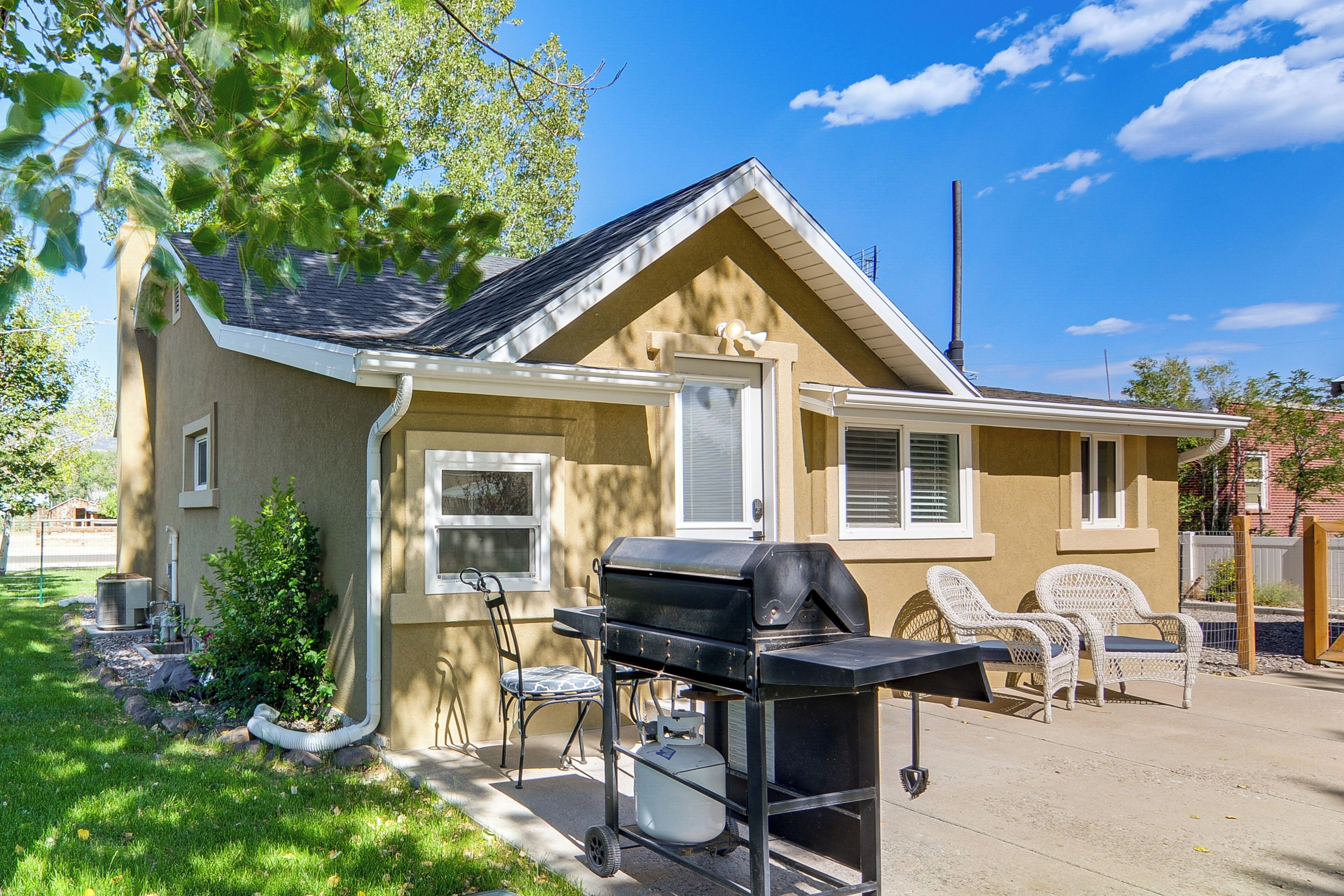 A house with a barbecue grill, outdoor seating, and a small garden.