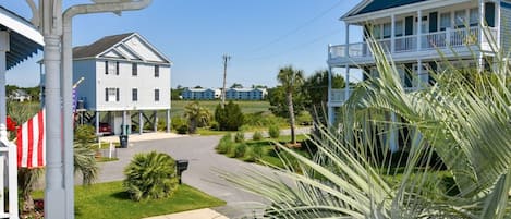A coastal hotel with a two-story structure, a covered porch, and a view of the ocean.