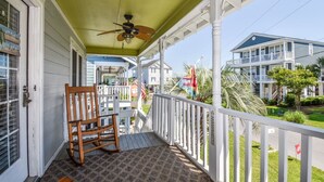 A porch with a ceiling fan, a rocking chair, and a view of neighboring houses. - Summer House - CANES, Three Bedroom, Two Bathroom, Second Row Community (Garden City Beach)