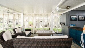 A covered outdoor seating area with wicker furniture and a bar counter. - Summer House - CANES, Three Bedroom, Two Bathroom, Second Row Community (Garden City Beach)