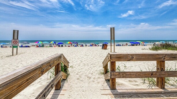 A beach with wooden boardwalks, umbrellas, and a sign prohibiting fireworks. - Summer House - CANES, Three Bedroom, Two Bathroom, Second Row Community (Garden City Beach)