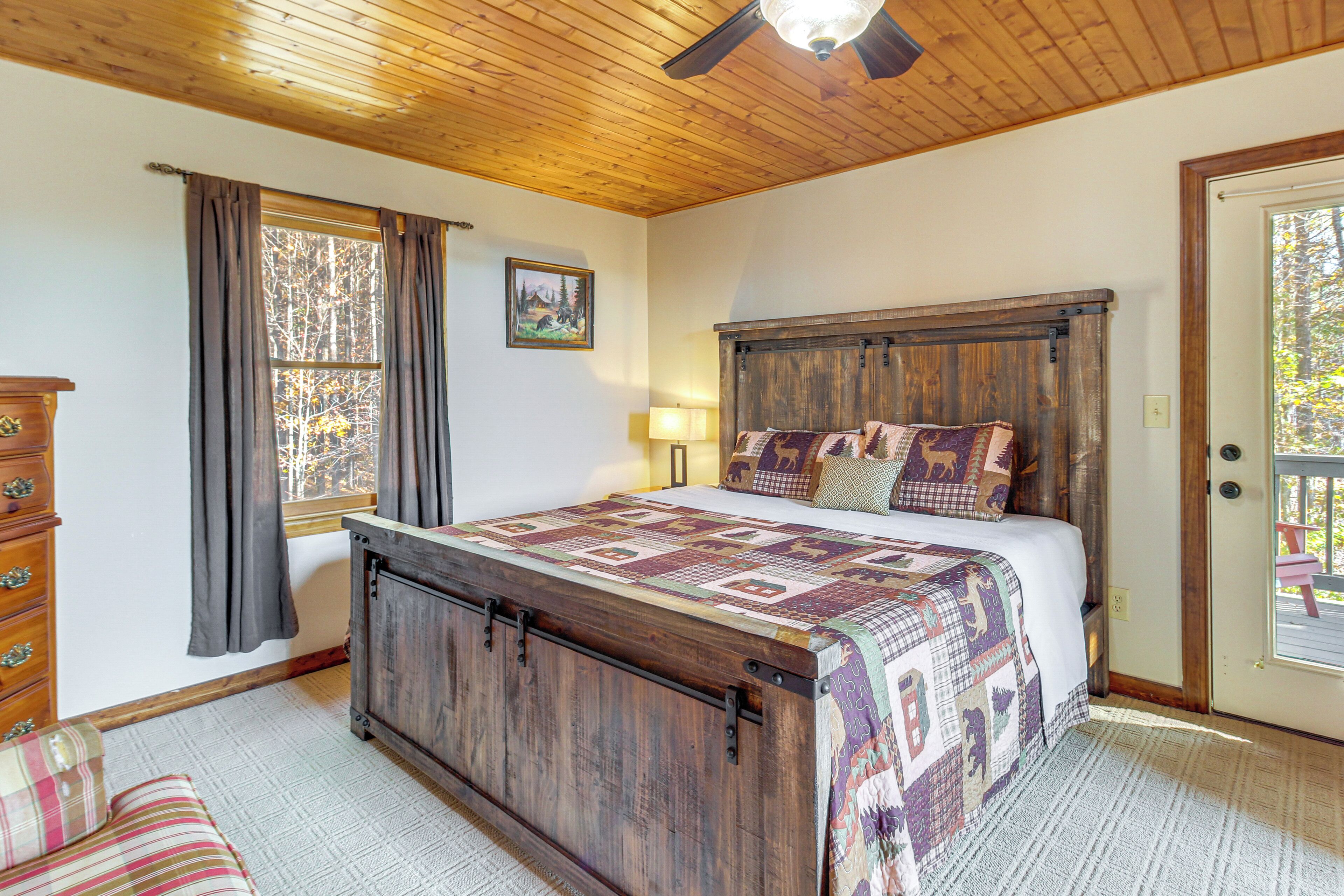 A bedroom with a wooden bed, a dresser, a window with curtains, and a door.