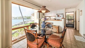 A dining area with a glass table, wicker chairs, and a view of the sea. - Oceanfront Kailua-Kona Townhome w/ Pool & Views! (Kailua-Kona)