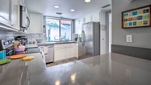 A modern kitchen with white cabinets, stainless steel appliances, and a large island. - Rancho Mirage Condo on Fairway w/ Resort Amenities (Rancho Mirage)