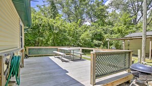 Une terrasse en bois avec des tables de pique-nique et un barbecue.