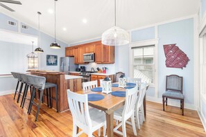 A modern kitchen with wooden cabinets, a central island, and pendant lighting.